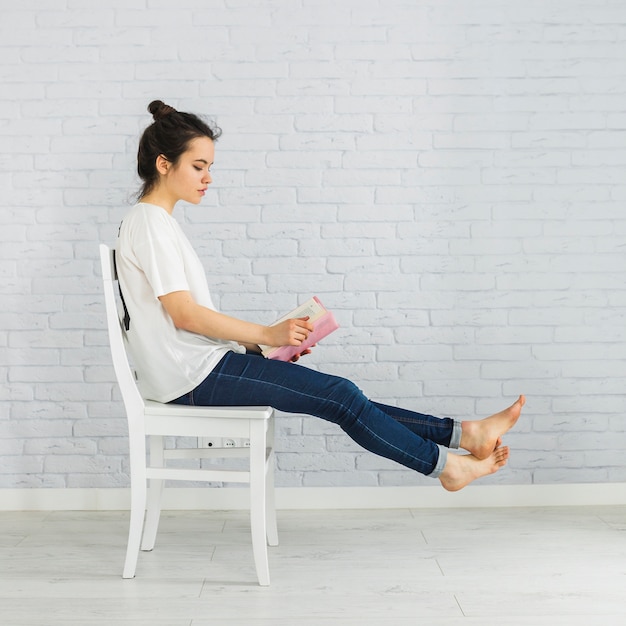 Playful woman reading book on chair