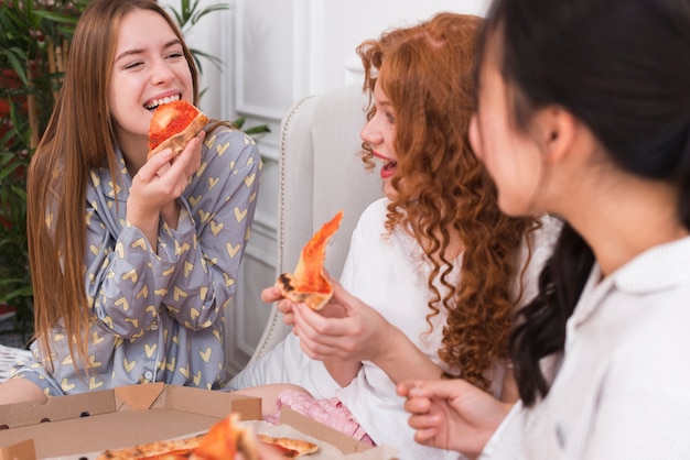 ピジャマパーティー中にピザを食べる遊び心のある女性