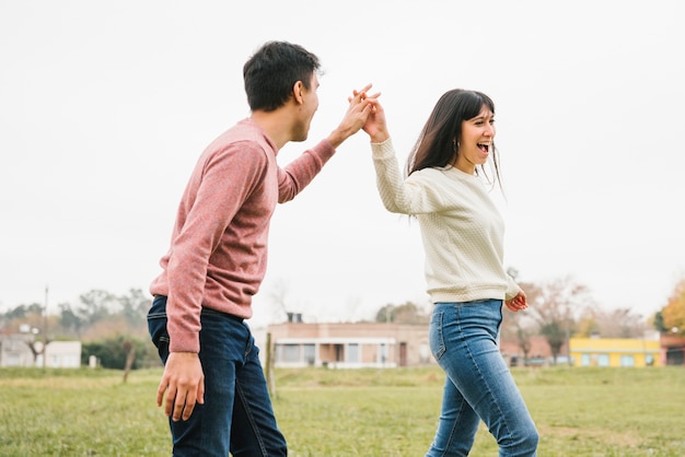 Playful young couple walking holding hands