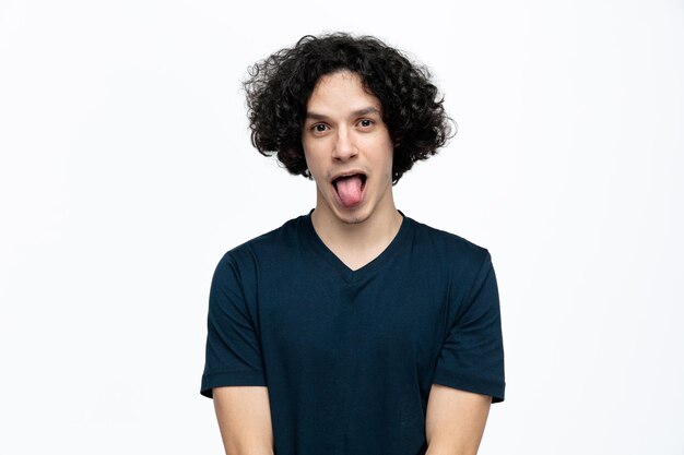 Playful young handsome man looking at camera showing tongue isolated on white background