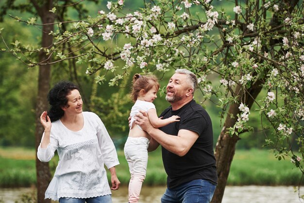 Playing around. Cheerful couple enjoying nice weekend outdoors with granddaughter. Good spring weather