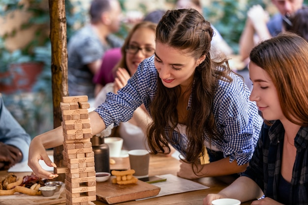 Playing jenga game at the restaurant with best friends and eating tasty snacks