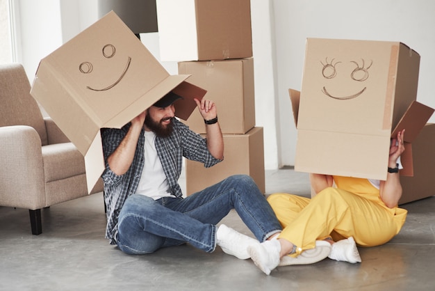 Playing with boxes. Happy couple together in their new house. Conception of moving