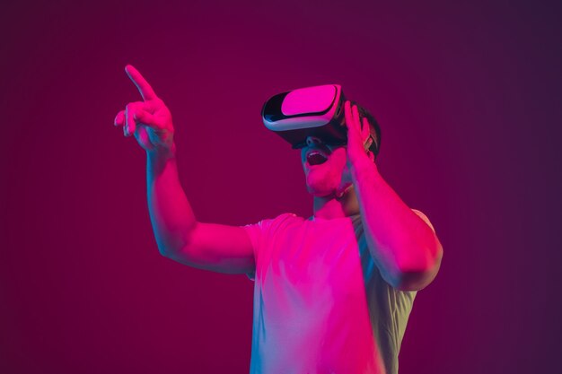 Играем с VR, стреляем, ходим. Портрет кавказского человека, изолированные на розово-фиолетовой стене студии.