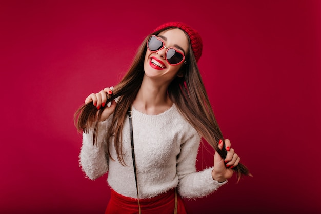 Pleasant caucasian girl in red hat isolated on claret space