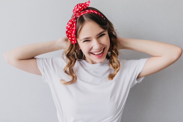 Free photo pleasant caucasian girl in white t-shirt posing. indoor portrait of laughing gorgeous woman with curly hairstyle.