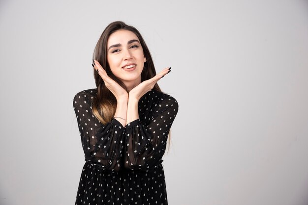 立ってポーズをとっている気持ちの良い若いブルネットの女性。