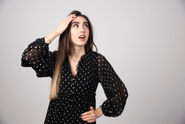 立ってポーズをとっている気持ちの良い若いブルネットの女性。