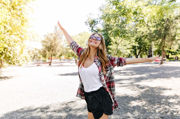 Pleasant slim girl dancing in summer park. Positive caucasian lady funny posing on nature.