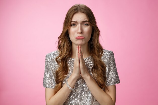 Please beg you. Clingy silly miserable supplicating young cute female curly-haired praying whining about cry press palms together asking please do favor need help, standing pink background