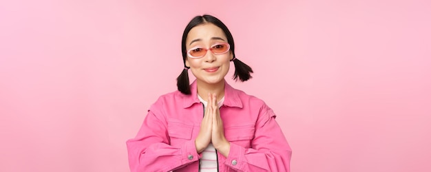 Please Cute asian girl asking favour begging standing against studio background Copy space