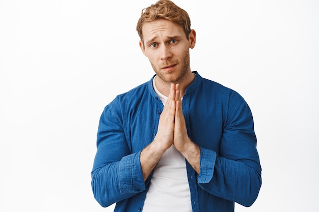 Free photo please help me. redhead handsome man begging for favour with sad nervous face, asking for favour, need something, frowning and pleading, standing, apologizing, standing over white background.