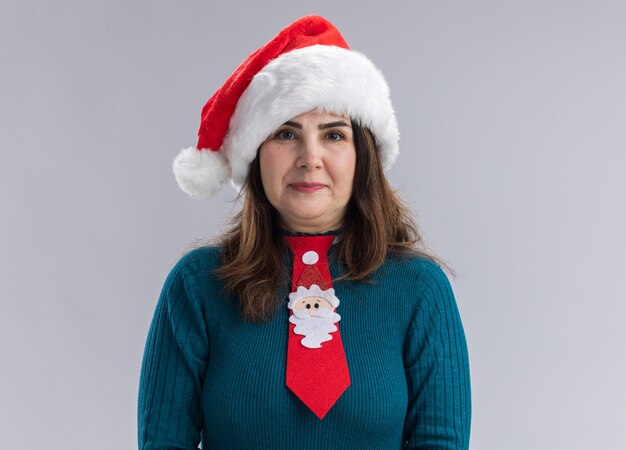 Pleased adult caucasian woman with santa hat and santa tie  isolated on white wall with copy space