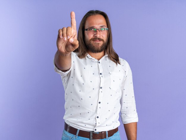 Pleased adult handsome man wearing glasses doing hold on gesture 
