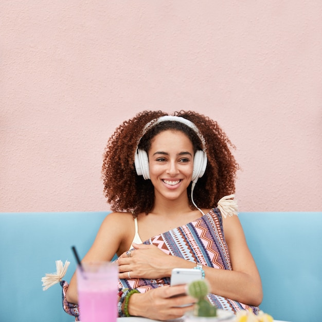 pleased African American female model enjoys favourite playlist, being meloman