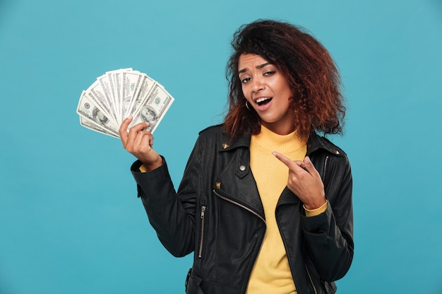 Pleased african woman in leather jacket holding money