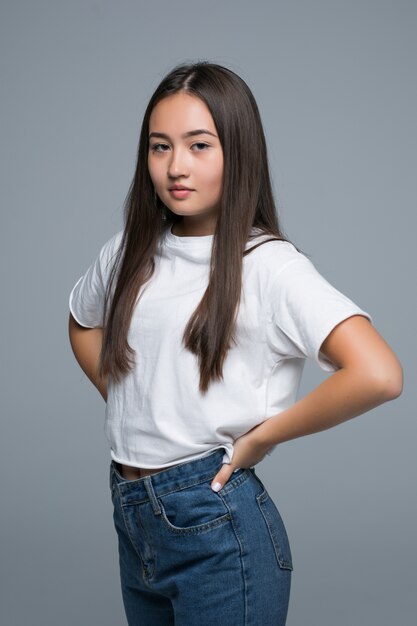 Pleased asian girl looking at the camera over gray background