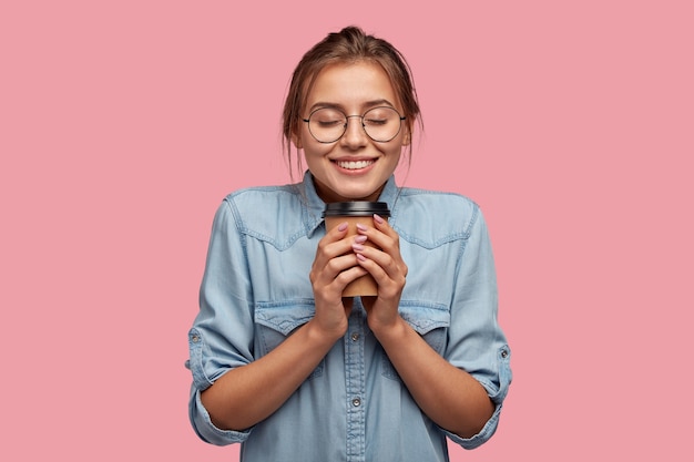 Pleased attractive woman holds takeaway coffee