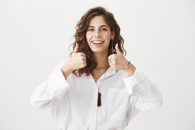 Pleased attractive woman thumbs-up in approval, recommend product