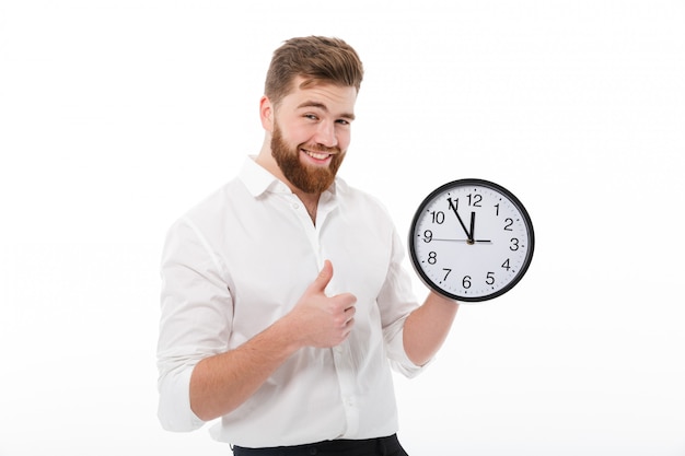 Pleased bearded man in business clothes holding clock