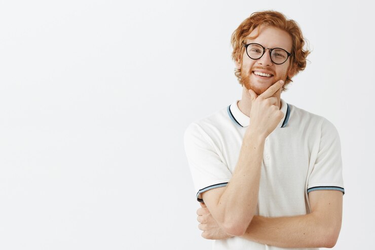Free Photo pleased bearded redhead guy posing against the white wall with glasses
