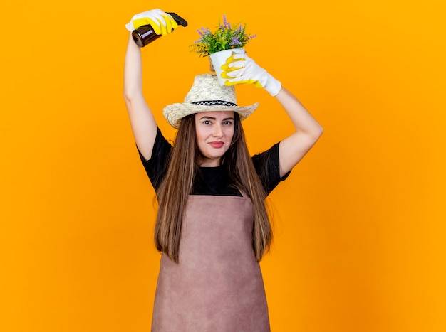 Foto gratuita felice bella ragazza giardiniere che indossa uniforme e cappello da giardinaggio