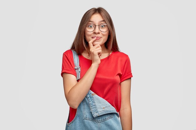 Pleased beautiful woman with long hair, has intriguing expression, looks with curiosity