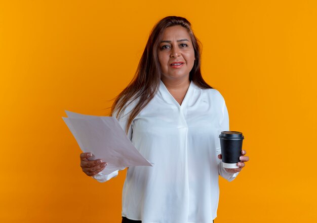 pleased casual caucasian middle-aged woman holding paper and cup of coffee