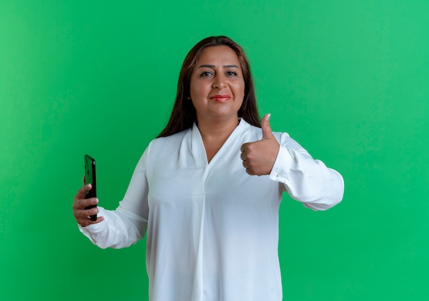 Pleased casual caucasian middle-aged woman holding phone her thumb up 