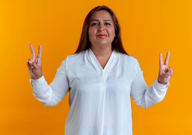 Pleased casual caucasian middle-aged woman showing peace gesture 