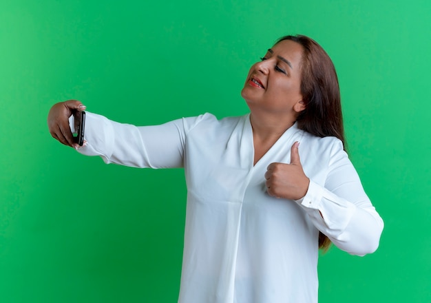 Pleased casual caucasian middle-aged woman take a selfie her thumb up 