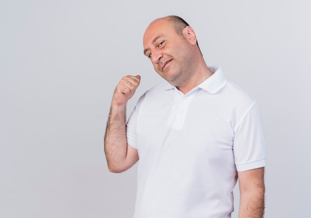 Pleased casual mature businessman looking at camera and pointing behind isolated on white background with copy space