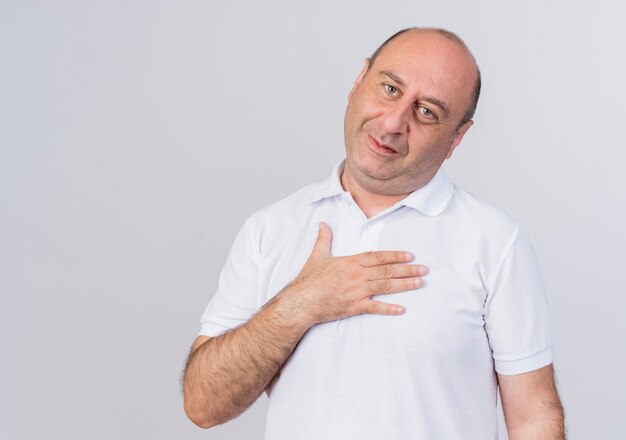 Pleased casual mature businessman putting hand on chest looking at camera isolated on white background with copy space