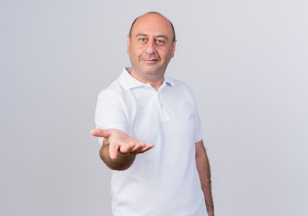 Pleased casual mature businessman stretching out hand towards camera isolated on white background with copy space