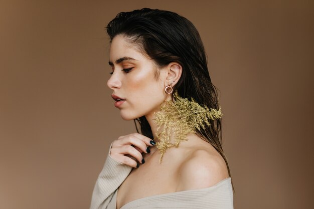 Pleased caucasian girl looking down. Sad black-haired woman posing with plant.