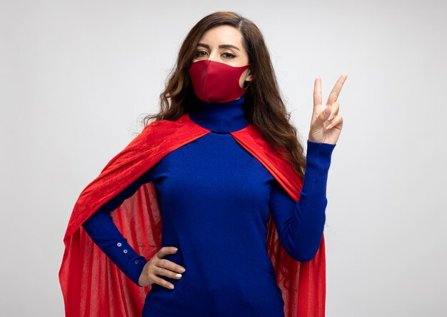 Pleased caucasian superhero girl with red cape wearing red protective mask