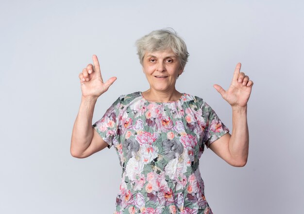 흰색 벽에 고립 된 두 손으로 기쁘게 노인 여성 포인트
