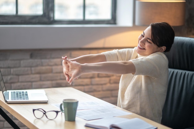 Free photo pleased female doing wrist stretches at the desk