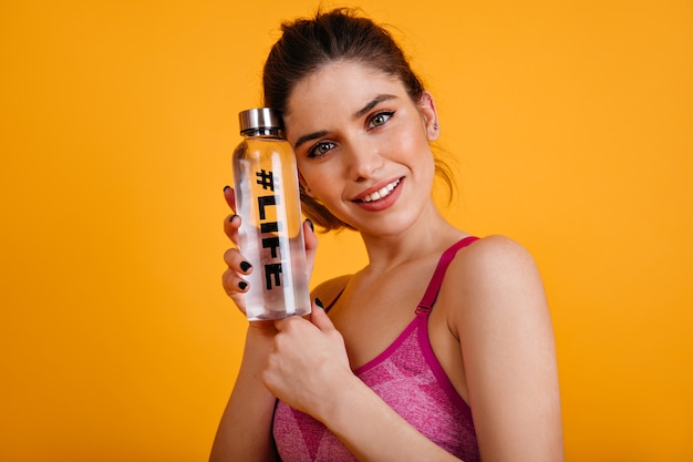 Free photo pleased fitness woman standing on bright wall