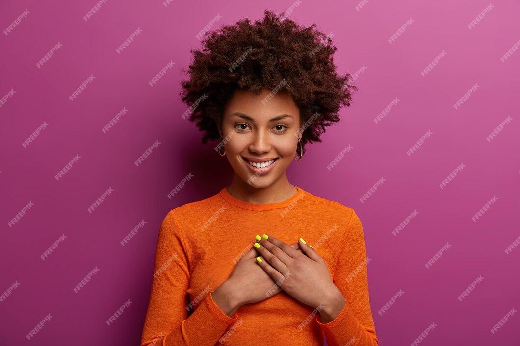 Free Photo | Pleased girl in orange jumper presses palms to heart ...