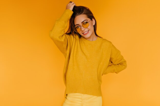 Pleased good-humoured girl in sweater posing with interested smile.