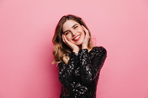 Pleased good-looking woman posing with sincere smile. Indoor portrait of cute european girl isolated on pink wall.