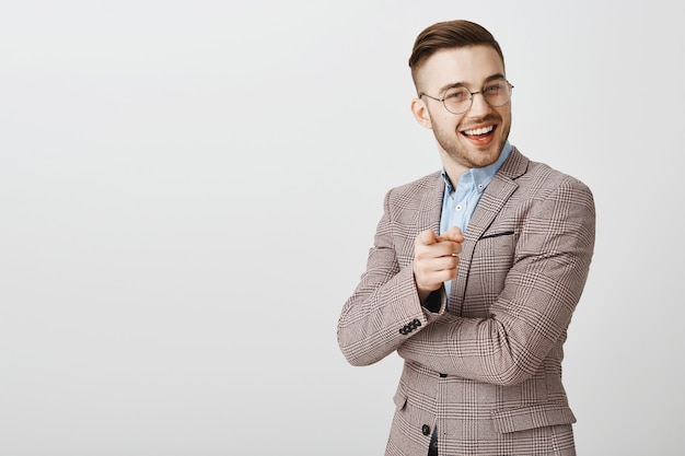 Free photo pleased handsome businessman pointing at person making good point, nice job, praising employee saying well done