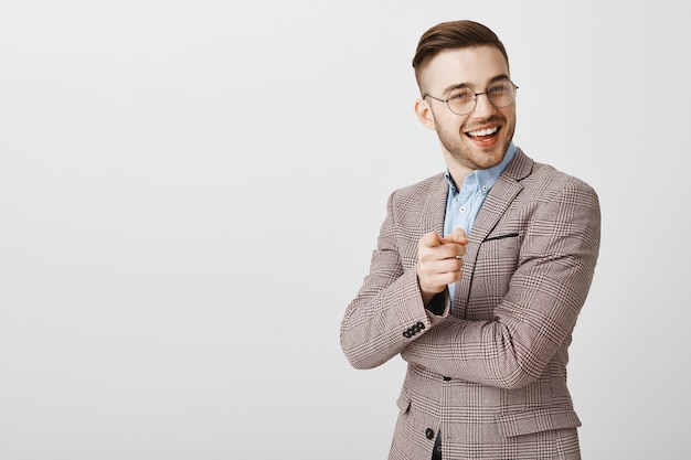 Pleased handsome businessman pointing at person making good point, nice job, praising employee saying well done