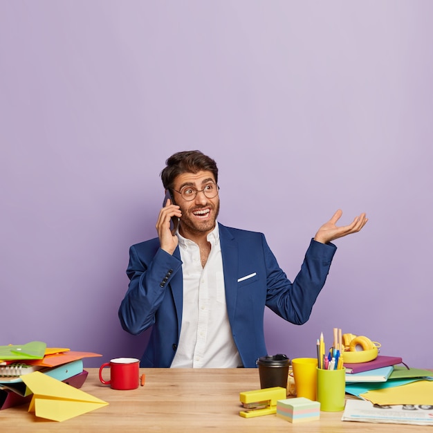 Pleased handsome businessman sitting at the office desk