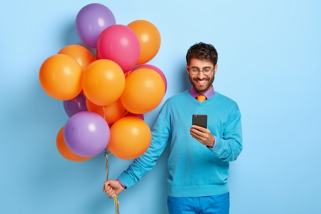 Pleased happy man gets message of congratulation on mobile phone, celebrates leaving university