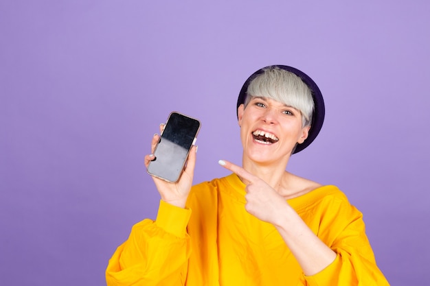 Довольная счастливая женщина указывает указательным пальцем на пустой экран, показывая современное устройство