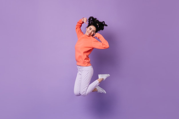 보라색 배경에 점프 기쁘게 일본 여자. 행복 한 아시아 젊은 여자의 스튜디오 샷입니다.