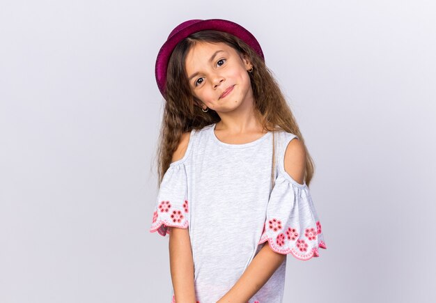 Довольная маленькая кавказская девушка в фиолетовой шляпе, изолированной на белой стене с копией пространства