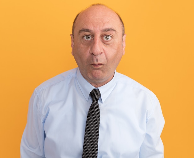 Pleased middle-aged man wearing white t-shirt with tie showing kiss gesture isolated on orange wall
